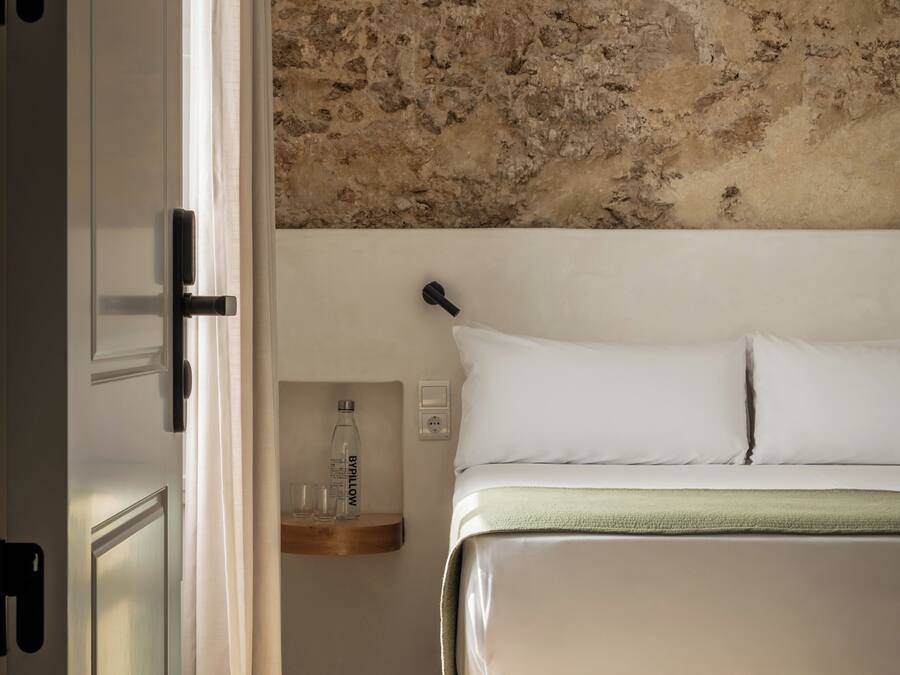 A bedroom with a bed, a nightstand, a bottle of water, and a pillow.