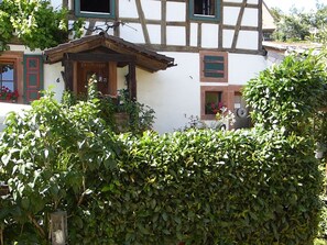 Ein traditionelles Fachwerkhäuschen mit einer Holztür, einer kleinen Veranda und einem Fenster mit Fensterläden.