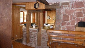 A rustic interior with exposed wooden beams, a stone fireplace, and a wooden bench.