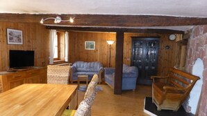 A wooden interior with a dining table, sofas, and a television.
