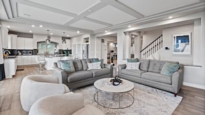 Ein geräumiges Wohnzimmer mit zwei grauen Sofas, einem Couchtisch und einer Küche im Hintergrund.