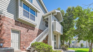 A two-story building with a brick facade, white siding, and a covered outdoor staircase. - New! Urban Oasis - Pool Access - Fireplace - 31 Day Rental (Aurora)