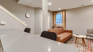 A modern living room with a sofa, a coffee table, and a dining area with a table and chairs.