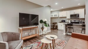 A modern living room with a flat-screen TV, a sofa, a coffee table, and a plant.