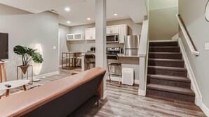 A modern apartment with a living room, kitchen, and staircase.
