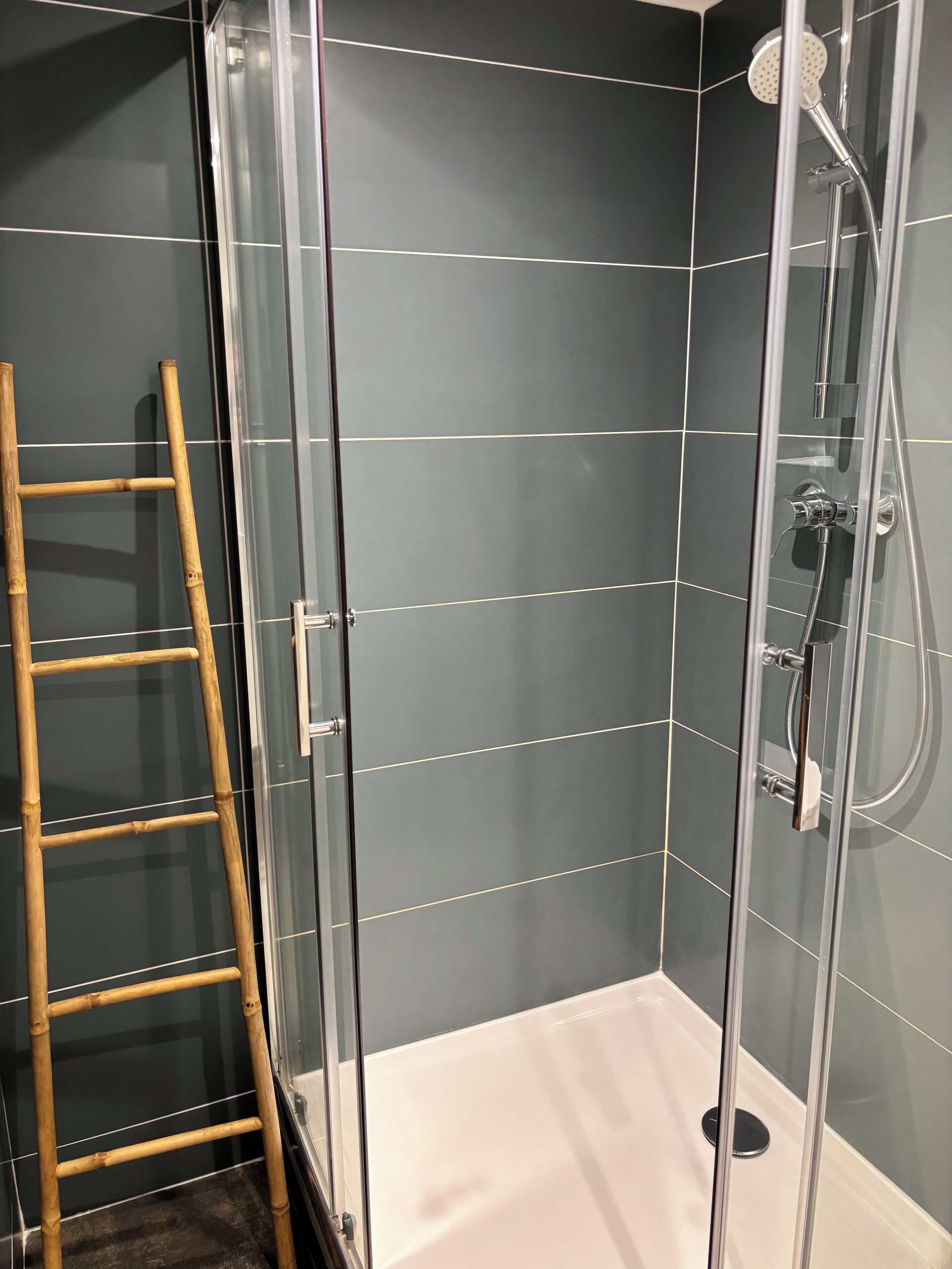 Zona de ducha con paredes de madera y azulejos, y un cabezal de ducha de mano.