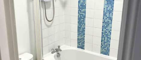 A bathroom with a white bathtub, a shower, and blue mosaic tiles on the wall.