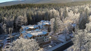 A multi-story hotel with a snow-covered landscape and mountains in the background.