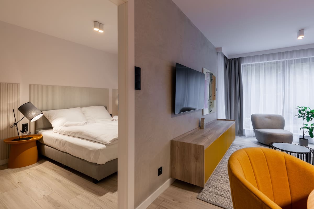 Una habitación de hotel moderna con una cama, un escritorio, una silla y un televisor en la pared.