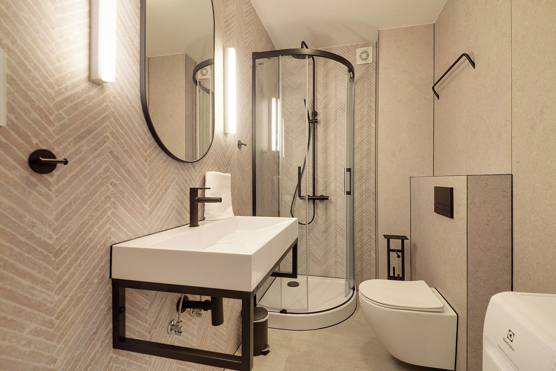 A modern bathroom with a white sink, a glass-enclosed shower, and a toilet.