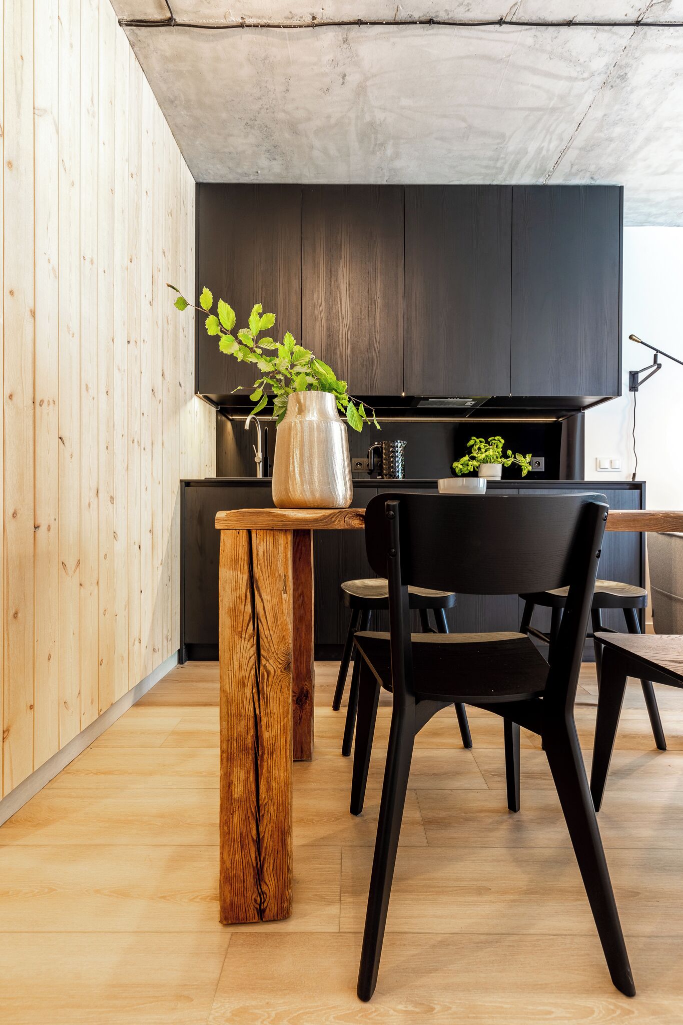 Una cocina moderna con armarios oscuros, una mesa de comedor de madera y una silla negra.