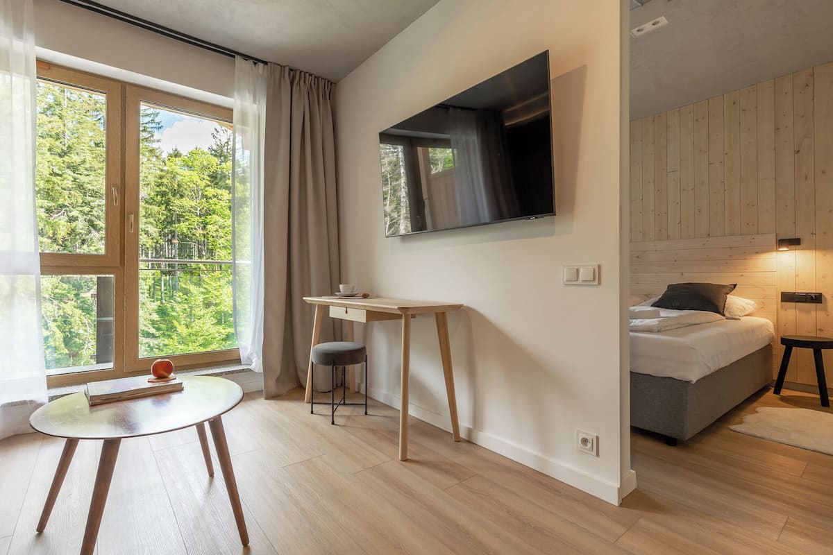 Un dormitorio moderno con cama, escritorio y televisión montada en la pared.
