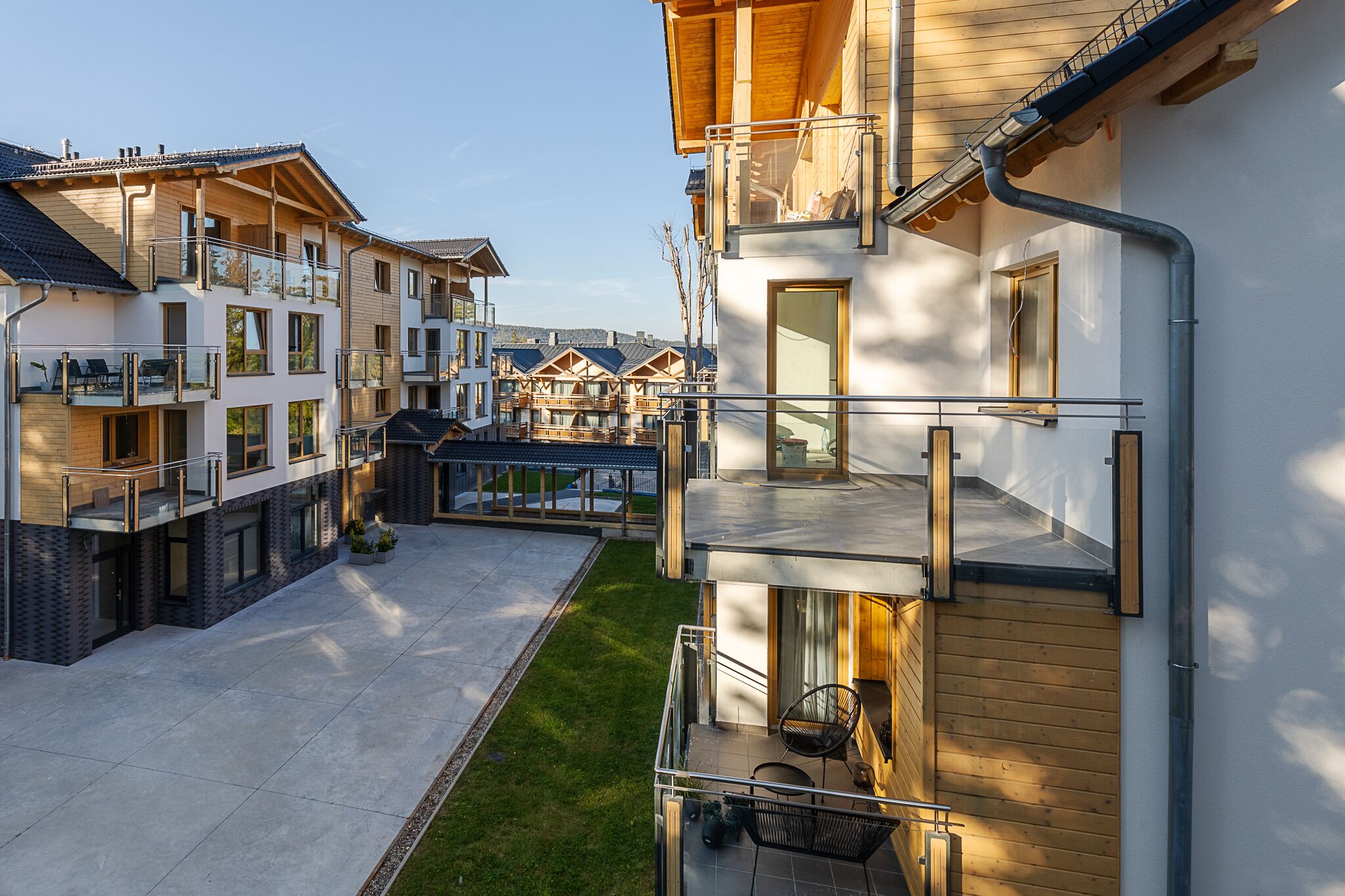A modern residential building with multiple balconies, a courtyard, and a well-maintained lawn.