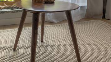 Ein Zimmer mit einem runden Tisch, einem grünen Glasgefäß und einer Kiefernzapfen.