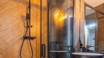 A modern bathroom with a glass-enclosed shower, a black sink, and a wooden floor.