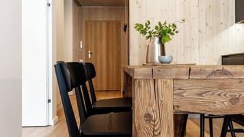 A modern dining area with a wooden table, black chairs, and a potted plant.