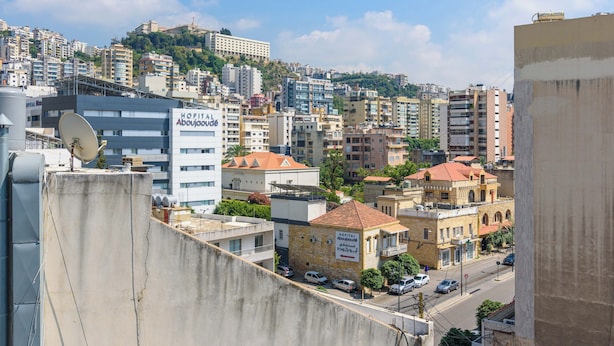 Paesaggio urbano con un mix di edifici moderni e tradizionali, tra cui un ospedale chiamato “Hôpital Aboujaoude” e un edificio con un'antenna parabolica.