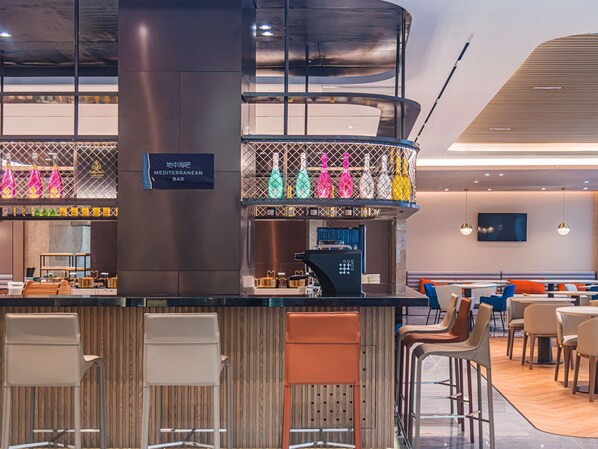 Un espace bar moderne doté d’un comptoir, de sièges et d’un écran de télévision.