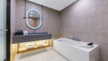 A modern bathroom with a large bathtub, a vanity with a mirror, and a shelf with towels.