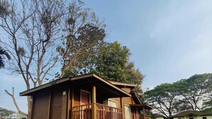 A wooden cabin with a balcony, surrounded by greenery and trees. - Jironi Resort (Raha Circle)