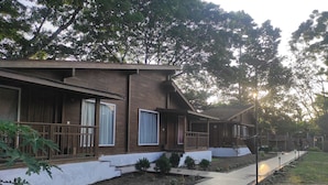 A row of wooden cabins with a paved walkway and a lamppost. - Jironi Resort (Raha Circle)