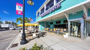 Une devanture de magasin avec une façade de couleur turquoise, des places assises à l’extérieur et une enseigne indiquant « DAQUIRI DECK ».