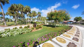 A landscaped area with palm trees, a grassy lawn, and flower beds.