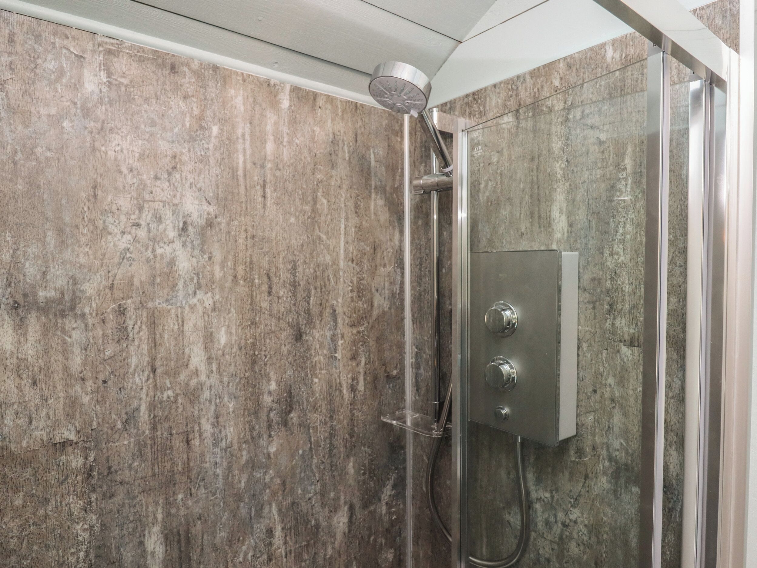 Une douche équipée d’un pommeau de douche à main et d’un panneau de commande.