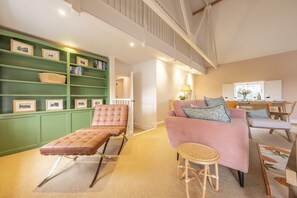 A spacious living area with a green bookshelf, a pink sofa, and a leather recliner.