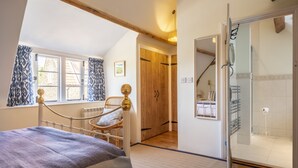 Une chambre à coucher avec un lit, une fenêtre avec des rideaux, une armoire en bois et une cabine de douche en verre.