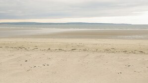 A beach with a wide sandy shore and calm water.