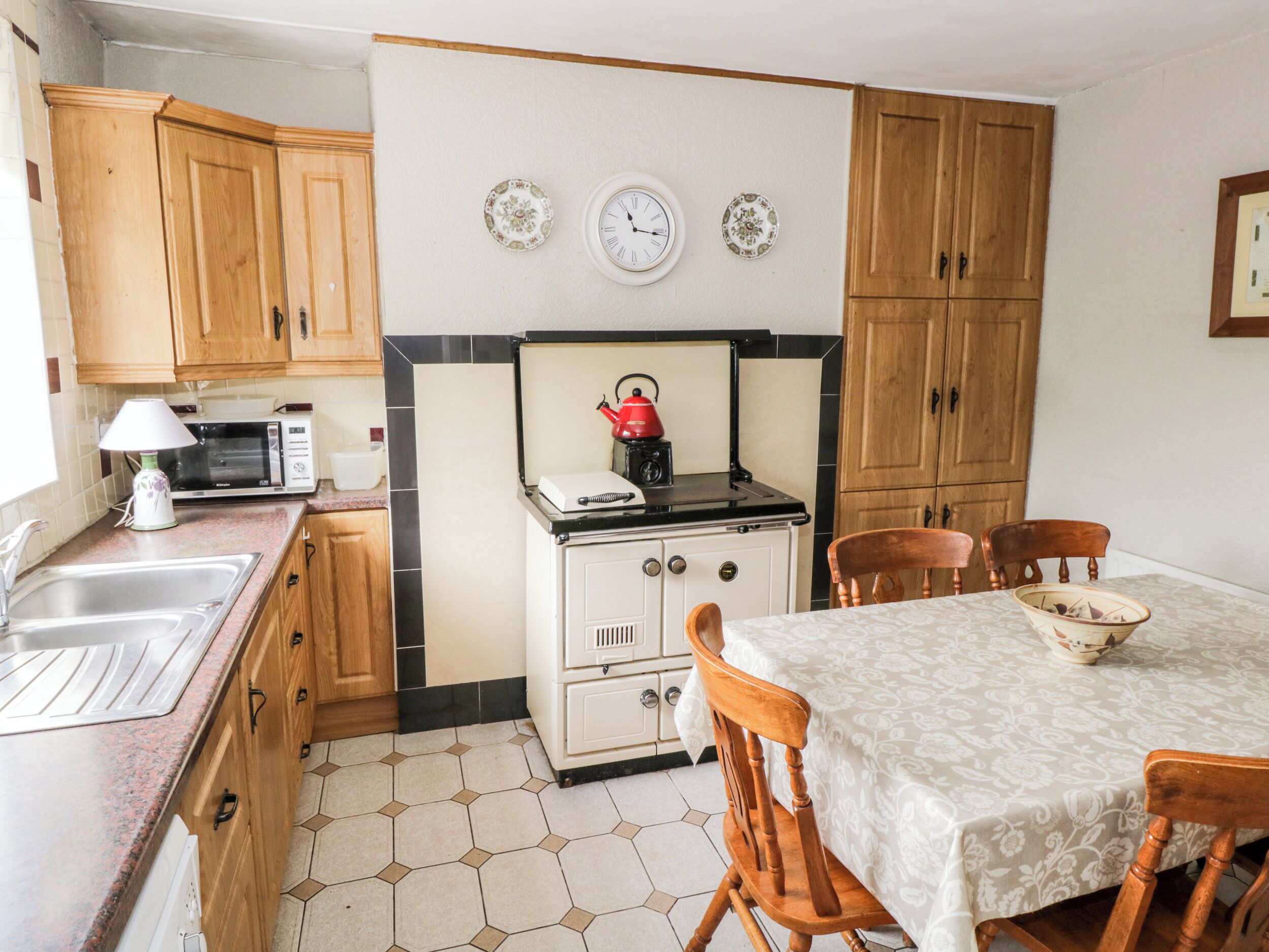 Une cuisine avec des meubles de rangement en bois, un four à micro-ondes, une cuisinière et une table à manger avec des chaises.