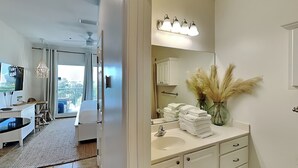 Un baño moderno con un espejo grande, tocador y vistas al balcón.