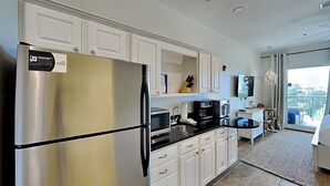 Una cocina moderna con armarios blancos, un refrigerador de acero inoxidable, una cafetera y un comedor con vistas.