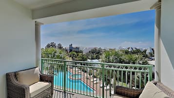 Uma varanda com móveis de vime, piscina e vista para edifícios.