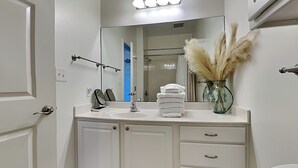 Un baño con tocador blanco, espejo, lavamanos e inodoro.