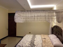 Un dormitorio con cama, puerta de madera y lámpara en el techo.