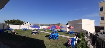 Un área de estar al aire libre con sombrillas azules y rojas, mesas y sillas.