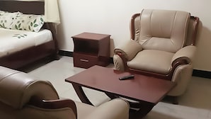 A room with a bed, a sofa, a chair, and a small table. - Joyce Hotel (Mubende)