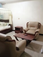 Una habitación con cama, sofá, sillón y una mesita.
