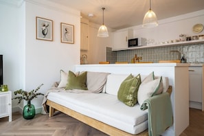 Relax in this stylish living space with a central sofa, side table, and kitchen area.