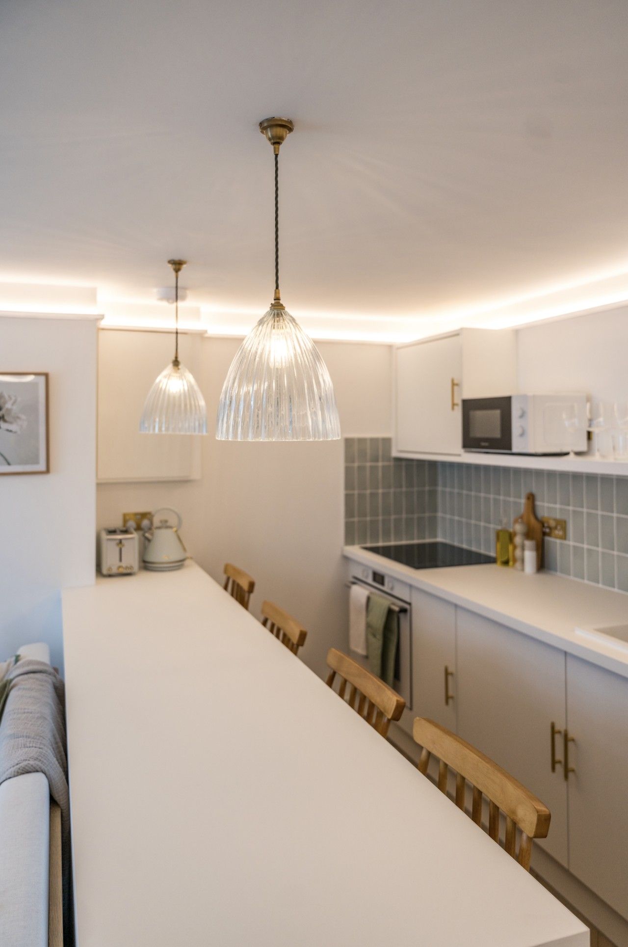 Una cocina moderna con armarios blancos, una isla central e iluminación colgante.
