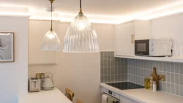 Una cocina moderna con armarios blancos, una isla central e iluminación colgante.