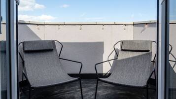 Two outdoor lounge chairs with a textured wall and a clear sky in the background.
