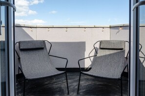 Two outdoor lounge chairs with a textured wall and a clear sky in the background.