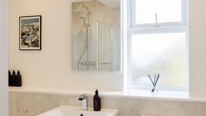 A bathroom with a bathtub, a sink, and a toilet. There is a window above the toilet and a mirror above the sink.