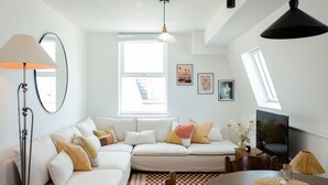 A modern living room with a sectional sofa, a dining table, and a TV.