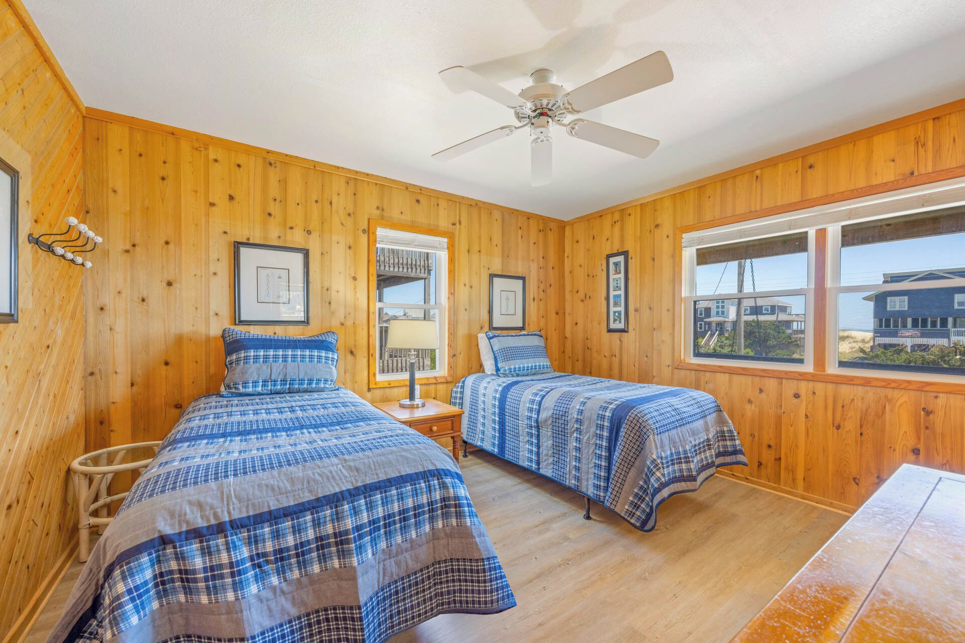 Drift off in your cozy twin beds with warm wood walls and a gentle ceiling fan. Wake to bright coastal light through large windows overlooking the beach neighborhood.