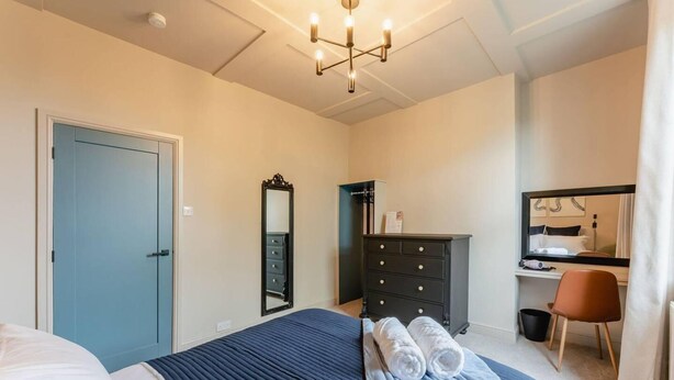 A bedroom with a bed, a dresser, a mirror, a desk, and a chair. - Swan House 3-bed Town House York - up to 5 Guests (York)