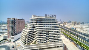 A modern multi-story building with the name "AZIZI" on the top.